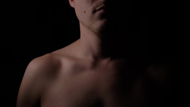 Naked upper body of a man. A man posing in the Studio in the dark.