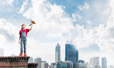 Concept of careless happy childhood with girl dreaming to become pilot