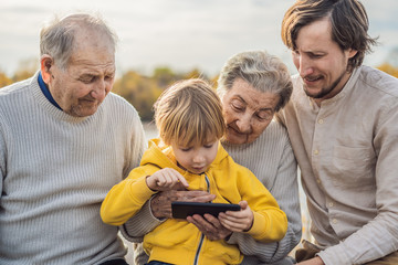The boy shows the photo on the phone to his grandparents