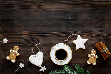 New Year gingerbread cookies. Gingerbread man near coffee, spruce branch, festive decoration on dark wooden background top view copy space