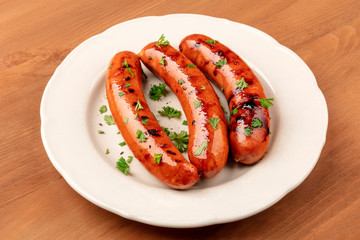 A photo of a plate of fried sausages on a dark rustic wooden background