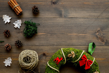 Preparing to Christmas. Traditional green christmas wreath near decorative elements on dark wooden background top view copy space