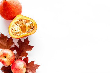 Composition with autumn vegetables and leaves in red and orange colors. Brown dried leaves, pumpkin, apple on white background top view copy space