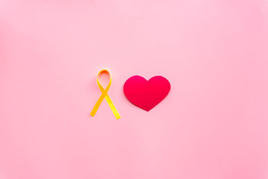 Endometriosis. Gynecological diseases concept. Symbolic yellow ribbon near heart sign on pink background top view copy space