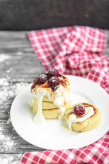 Cottage cheese pancakes with strawberry jam on white plate on grey wooden background. Healthy breakfast.