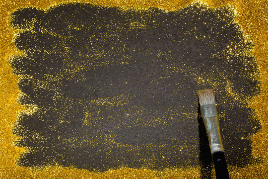 Paint brush revealing copy space on gold glitter luxury background