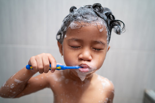 toddler brush her own teeth while taking a shower