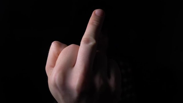 male Hand Showing Middle Finger out of the Darkness. 4K slow motion