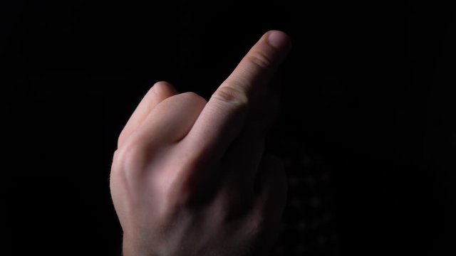 male Hand Showing Middle Finger out of the Darkness. 4K slow motion