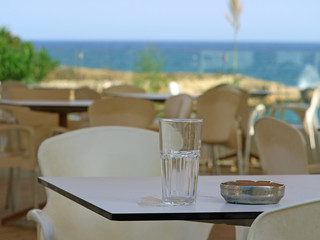 emty glass and ashtray on table in a restaurant near the beach