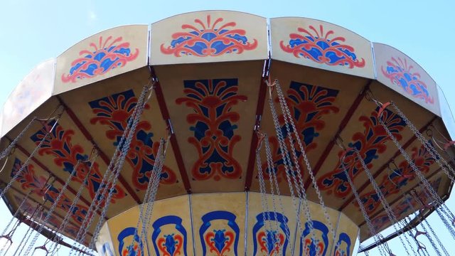 Swing ride top part with seat chains attached spinning against bright blue sky