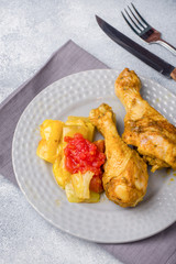 Baked chicken leg Shin with vegetables tomato zucchini on a plate.