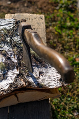 Axe stuck in birch bark on a birch log in the yard on the street