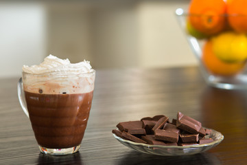 Cup of hot chocolate with pieces of dark chocolate background.