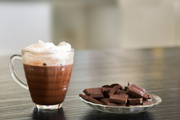 Cup of hot chocolate with pieces of dark chocolate background.