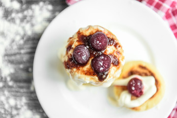 Cottage cheese pancakes with strawberry jam on white plate on grey wooden background. Healthy breakfast.