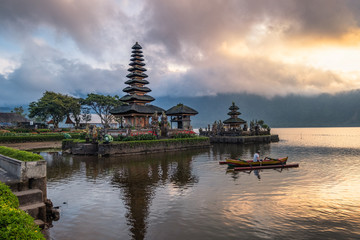 Ancient Pura Ulun Danu Bratan temple with tourist paddle and sunrise sky
