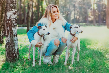 beautiful adorable happy blonde woman owner with her two white whippet outdoor