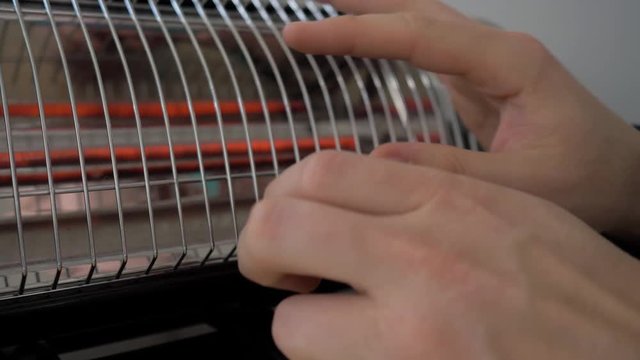 Man warming his hands near the heater. 4K