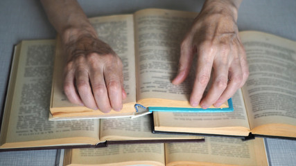 Naklejka premium Elderly person hands with opened books, close up, selected focus, blur