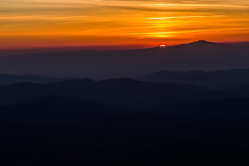 Beautiful sunset with sun coming down behind various layers of mountains