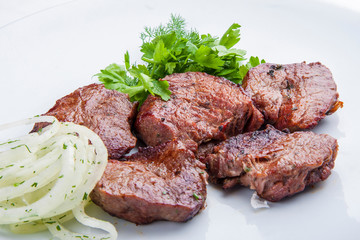 Veal shashlik with onion on a white plate