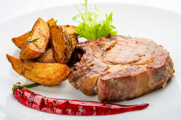 Steak from pork chop with potatoes on a white plate