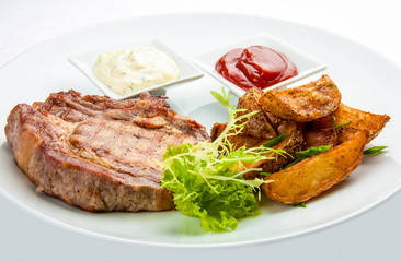 Steak from pork chop with potatoes on a white plate