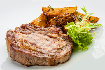 Steak from pork chop with potatoes on a white plate