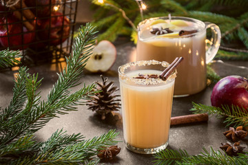 Apple cider cocktail with cardamom and star anise on black table with fir tree branches. Christmas...