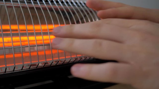 Man warming his hands near the heater. 4K