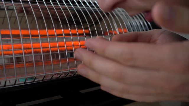 Man warming his hands near the heater. 4K
