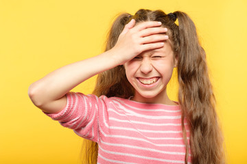 ashamed smiling girl covering her forehead with a hand. embarrassment and shame emotion.