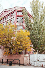 The ancient production building of red color under the blue sky with clouds in the autumn afternoon.