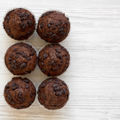 Chocolate muffins on white wooden table, top view. Flat lay, overhead, from above. Copy space.