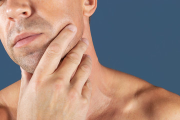 Obraz premium Sad depressed man in pain holding his cheek. Portrait of a man on blue background. emotion facial expression. feelings and people reaction. Toothache