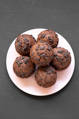 Chocolate cupcakes on pink plate on black background, top view. Flat lay, from above, overhead. Close-up.