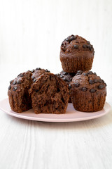 Chocolate cupcakes on pink plate on white wooden background, side view. Closeup.