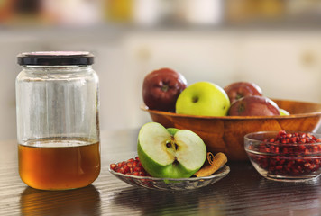Apples with honey jar , pomegranate seeds and cinnamon sticks.