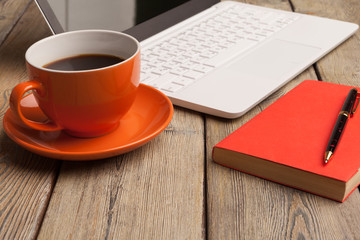 A cup of coffee on the orange plate on the wooden table. Office interior