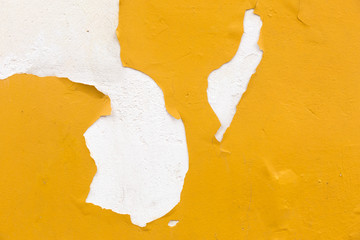 Grunge wall with peeling yellow paint texture.