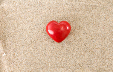 Red heart, on sandy background.