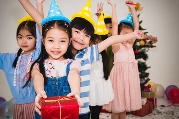 Childhood and celebration concept - happy kids with gifts on birthday party.