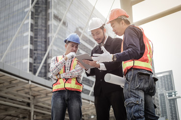 Asian engineer man and construction workers discussing on plan building project in the city