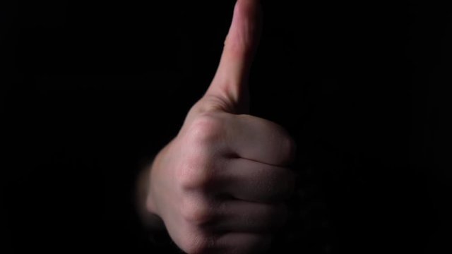 Hand Gestures coming out of the dark into the light. Thumbs up into the camera. 4k slow motion