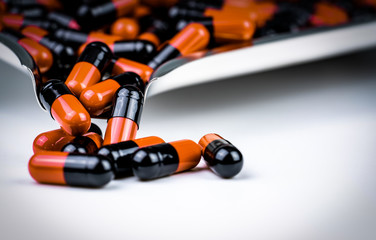 Orange and black capsule pills on drug tray. Antibiotics drug resistance. Global healthcare....