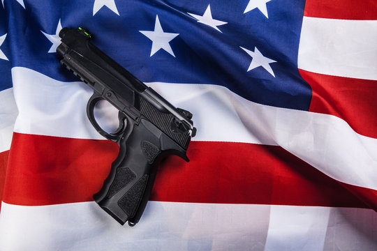 Handgun lying on American flag. Weapon problem concept