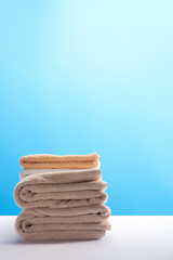 stack of clean fresh towels on white table on blue background