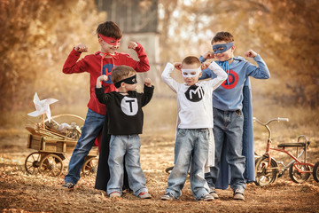 Four boys play a superhero in the playground