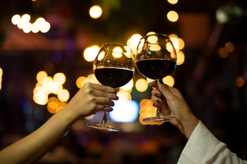 Women with friend celebrating Christmas party dinner with clinking glass of wine in Night Club.